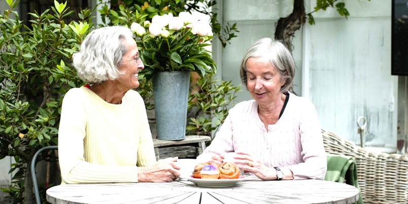 To smilende ældre kvinder drikker kaffe