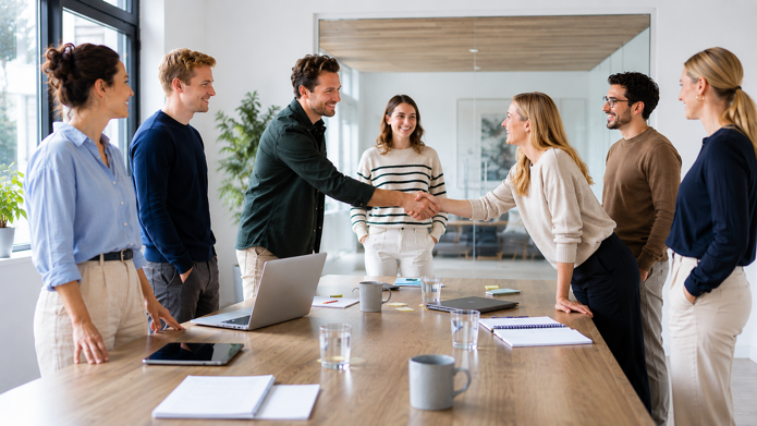 Colleagues shaking hands during a meeting in a modern Scandinavian office environment