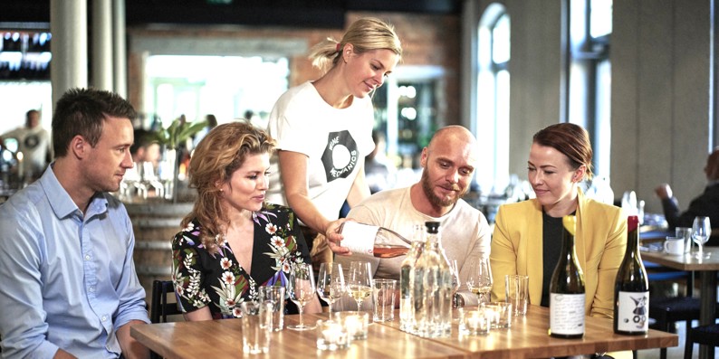 Tjener hælder vin op til restaurantgæster