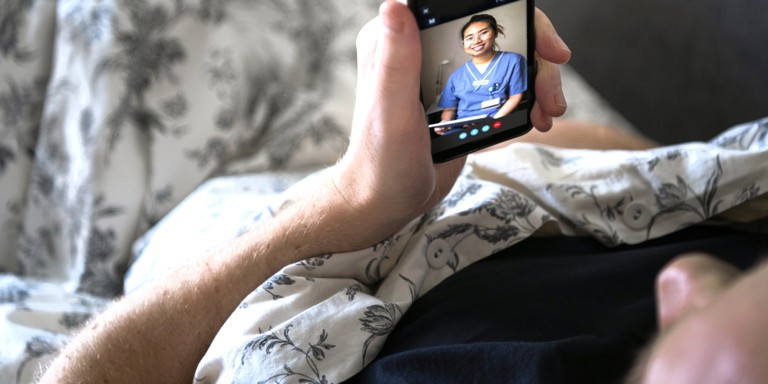 Sick man in bed facetiming with doctor