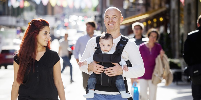 Forældrepar på gågade - far med baby i sele på maven