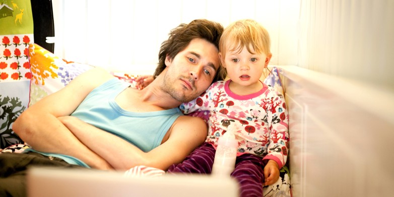 A parent staying home with a sick child and resting together on a sofa