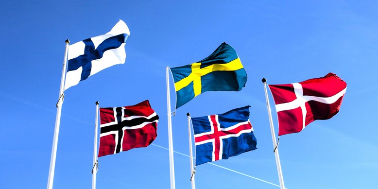 Nordiske flag vejrer mod blå himmel