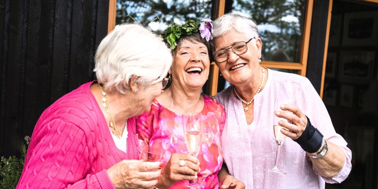 Three elderly women toasting and laughing