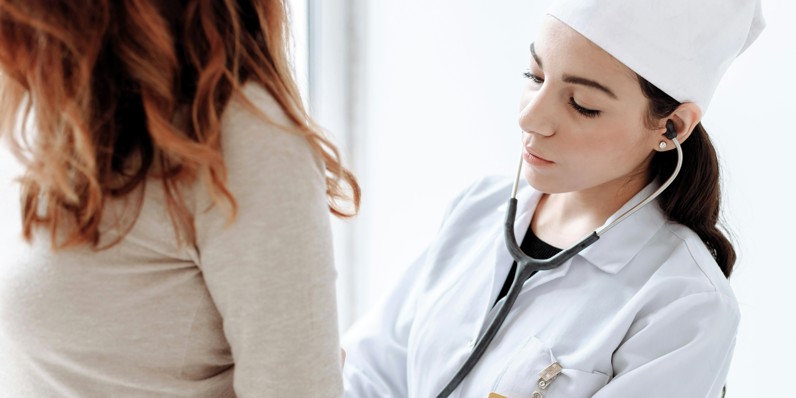 Læge tjekker patient med stetoskop