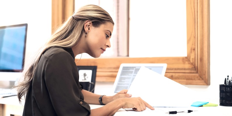 Young woman reading a document at a table