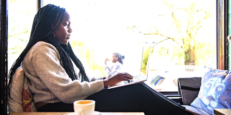Kvinde arbejder ved computer i cafevindue