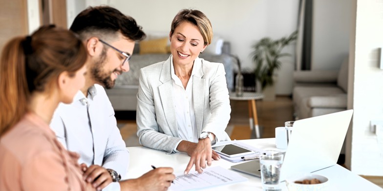 A bank advisor helping a couple review and sign financial documents